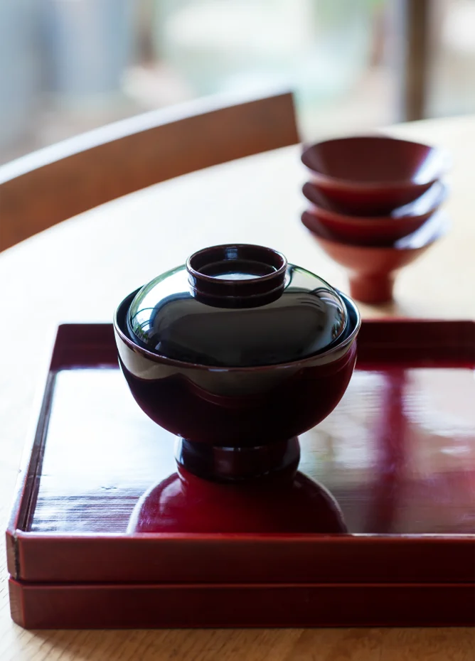 お雑煮用のお椀も折敷も、丁寧に拭き上げて育ててきたもの。奥は作家ものの和紙に漆を塗った小鉢。